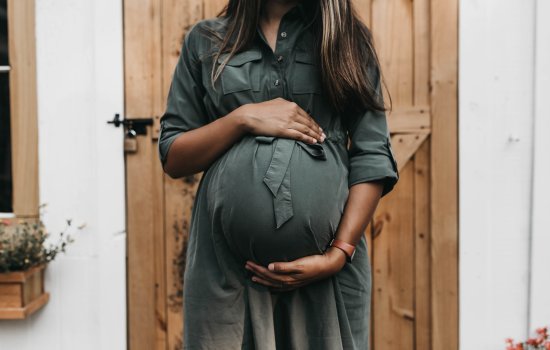 A pregnant woman holds her hands above and below her pregnancy.