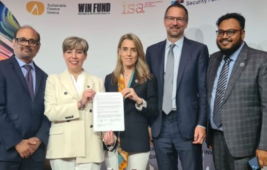 Five people standing in a line shoulder to shoulder, including two women holding a signed document.