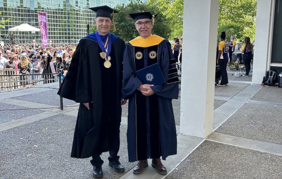 Igor Lednev and Jürgen Popp stand in academic regalia on the academic podium following UAlbany's 2023 undergraduate commencement ceremony.