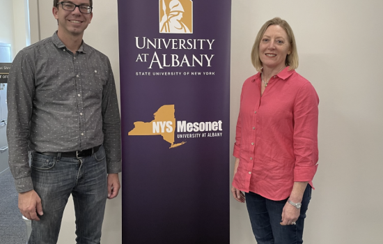 Nick Bassill and Jeannette Sutton stand in front of purple NYS Mesonet step and repeat banner.