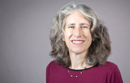 A smiling Julie Novkov in a dark read sweater and necklace