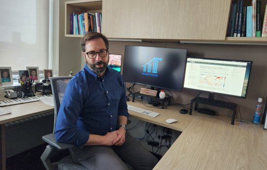 Brian Rose sits at his desk in front of dual computers on the Project Pythia website.