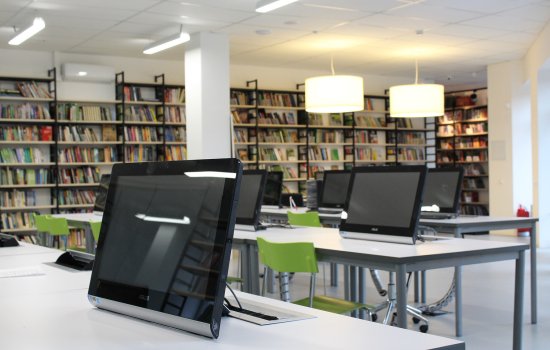 A library with rows of tablet computers at desks.