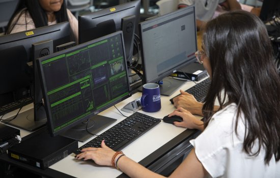 A female student works at a cybersecurity computer workstation inside the digital forensics lab at UAlbany.