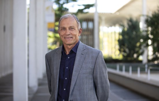 Chemist Igor Lednev stands on the Academic Podium in a grey suit.