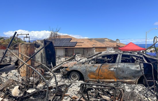 A charred car sits in front of a damaged home in Lahaina due to the Maui wildfires.