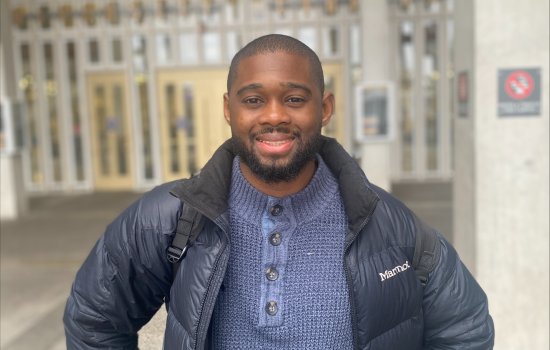 Graduate Ambassador Xavier posing in front of the University at Albany's library.