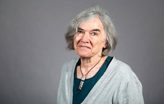 Marlene Belfort smiles in a deep teal blouse and gray cardigan against a dark gray background.