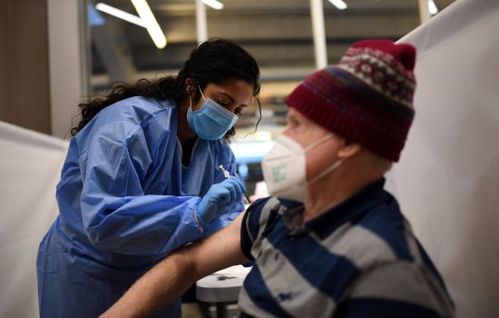An older man is vaccinated by a nurse from the NYS National Guard at Yankee Stadium in the Bronx.