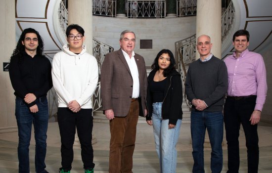 A group of six people stand in a line inside Schenectady City Hall smiling, including Mayor Gary McCarthy.