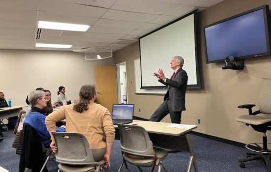 Dr. Marc Stern stands at the front of a classroom filled with people, talking to them about correctional health care.