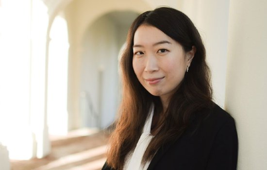 Haruka Takayama smiles in a sunlit hallway while wearing a white blouse and black blazer