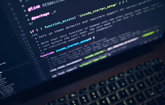 A string of pink, green, yellow, white and blue code on a laptop screen.