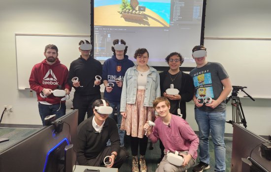CEHC Instructor Claire Thomas stands in the middle of students wearing Meta Quest 2 headsets in front of a projector screen inside a computer lab at the Science Library.
