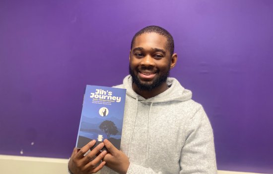 Xavier McClean posing with his novel, Jih's Journey. 