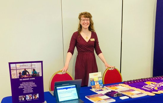 Chloe Glenn posing behind a table at a recruitment fair. 