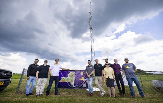Mesonet researchers stand in front of the Lake Placid site on a cloudy day.