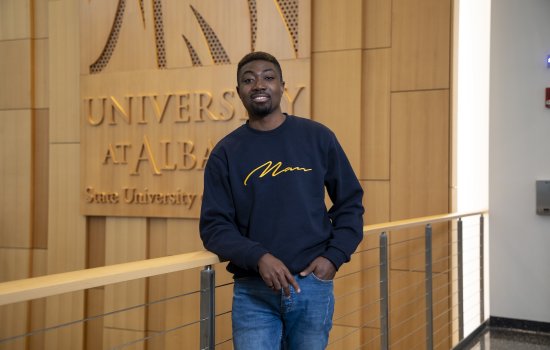 George Akwetey in front of UAlbany sign