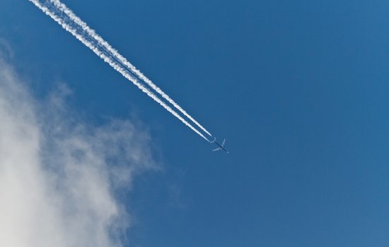 Contrails form across the sky behind a jet aircraft engine.