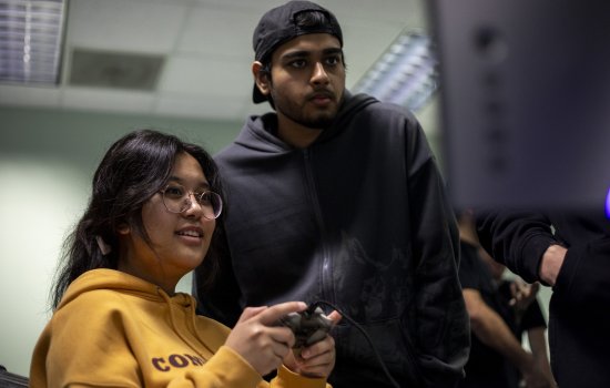 Students look at a computer screen with preparing game design projects for Showcase.