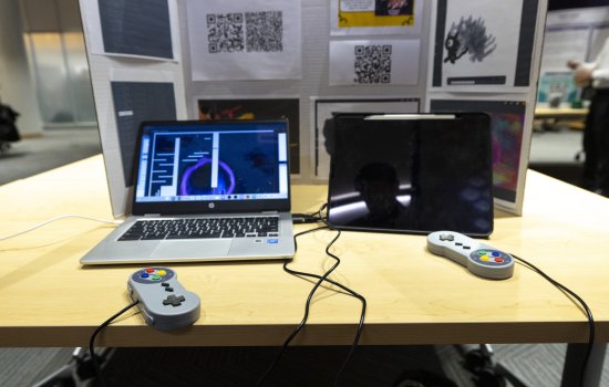 Laptops connecting to gaming controllers sit on a table inside the ETEC shared training room.