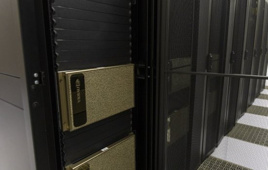 A close-up of a silver rectangular GPU system installed in a row of tall, black server racks.