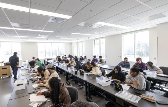 students work on projects at communal tables in class.