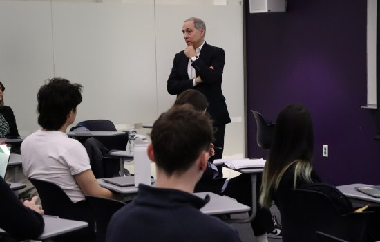Man in a suit standing in front of a class of students. 