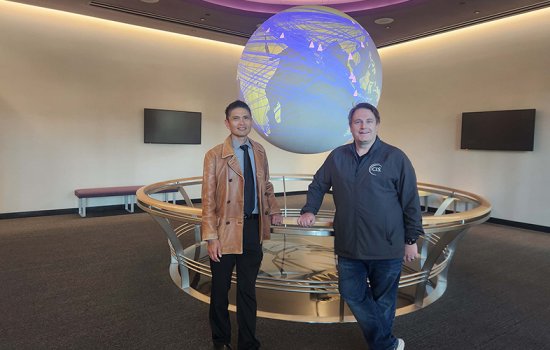 CEHC's Ariel Pinto and Center for Internet Security's Sean Atkinson stand in front of the Science on a Sphere globe at ETEC.