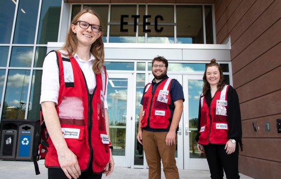 Nancy Kreis, Mike Clahane and Erin Golden stand in front of the ETEC building in American Red Cross vests.