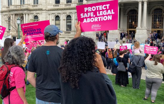 People holding up "protect Safe, Legal Abortion" and other signs at Abortion Rights rally outside the NYS Capitol building.