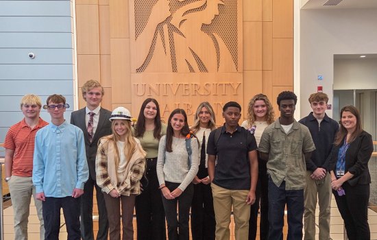 High school seniors from the New Visions program take a photo in front of the Minerva logo at ETEC.