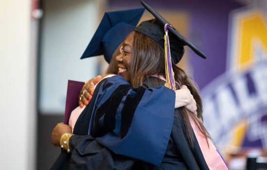 A student hugs her professor at commencement.
