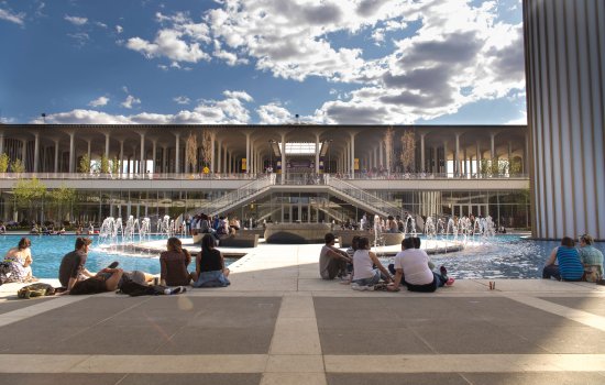 Students sit in the shadow of the carillon and put their feet in the Main Fountain's waters during a bright and beautiful summer day at UAlbany.