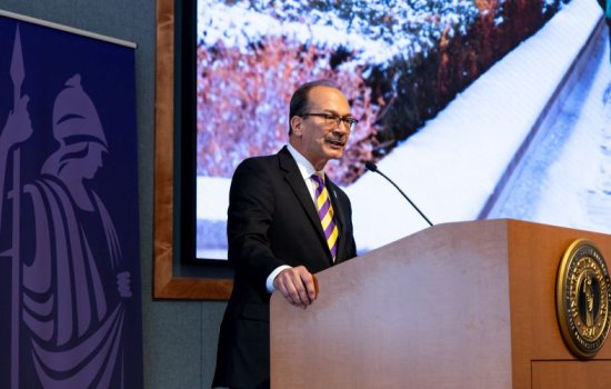 A man in a stiped tie speaks at a lecturn