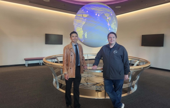 CEHC's Ariel Pinto and Center for Internet Security's Sean Atkinson stand in front of the Science on a Sphere globe at ETEC.