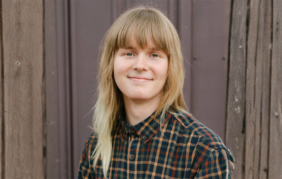 Portrait of a smiling Clark Mattoon standing in front of a wooden fence.
