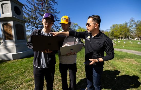 Students Micah Wang and Weiming Lan stand with Associate Professor Rui Li at the site of the Civil War memorial at Albany Rural Cemetery in Menands, N.Y. (Photo by Patrick Dodson)