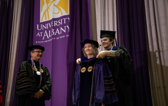Doctoral student being hooded by advisor.