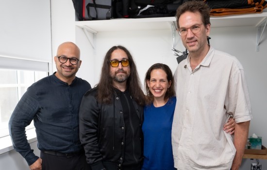 Four people, including three men and a woman, pose for a picture together inside a room