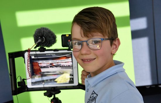 Boy standing in front of ipad smiling