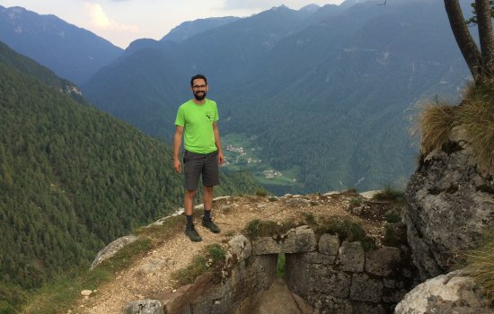 Justin Minder stands atop a rock-climbing cliff in Serrada, Italy during the International Conference on Alpine Meteorology in 2019.