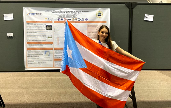 Kayleen Torres Maldonado displays the Puerto Rican flag in front of her research at the American Meteorological Society Annual Meeting in Boston, January 2020.