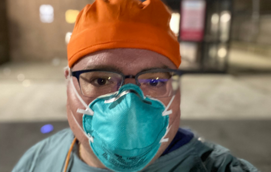 MPH student Lou Rotkowitz wears a blue face mask and an orange hat for a selfie.