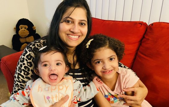 Prachi Bharadwaj smiles and holds her two young daughters on her lap