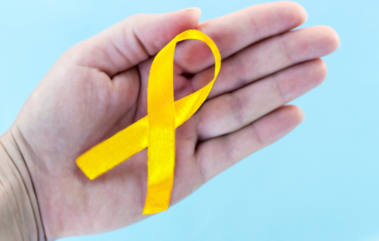 Photo of a person's palm holding a a yellow ribbon