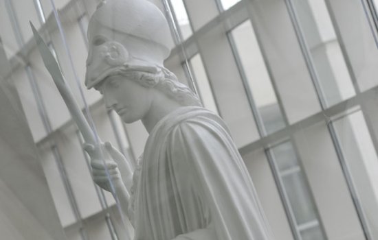 A white statue of Minerva stands in the Science Library atrium. Glass windows are behind her.