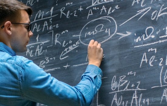 UAlbany student writing mathe problems on a chalk board