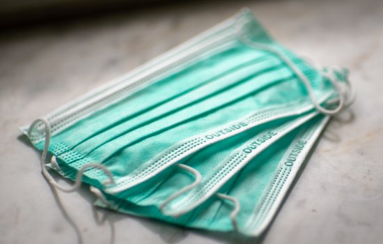Three blue-green face masks sit on a grey surface.