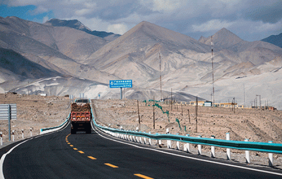 Truck driving up a road with mountains in distance